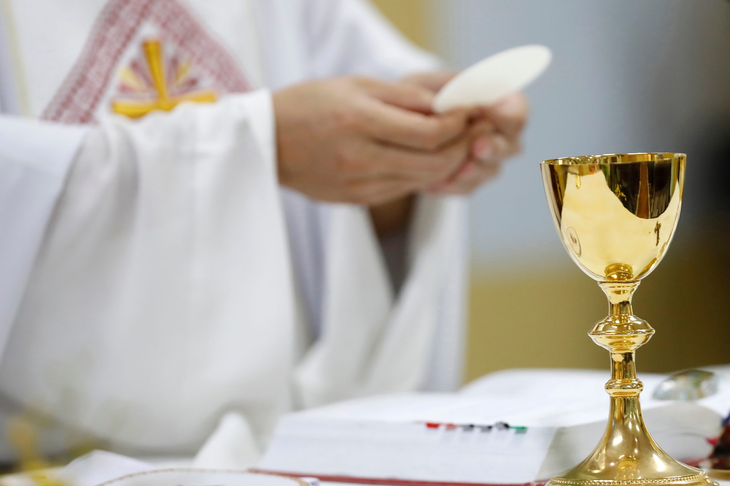 Priest holding a communion host and chalice during Catholic Mass